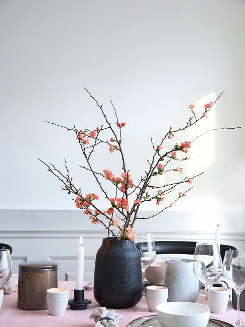 gałązki wiśni w matowym ciemnym wazonie na stole