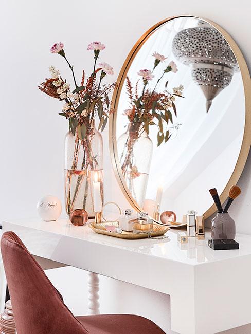 biała toaletka ze złotym lustrem i różowym tapicerowanym krzesłem