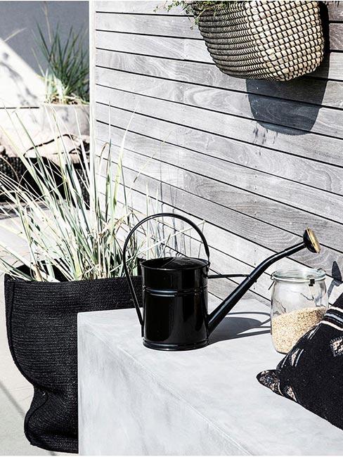 czarna konewka na szarym tarasie