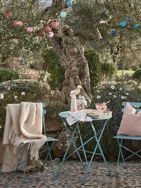 Mały estetycznie zaaranżowany ogród, stoliki pod drzewem