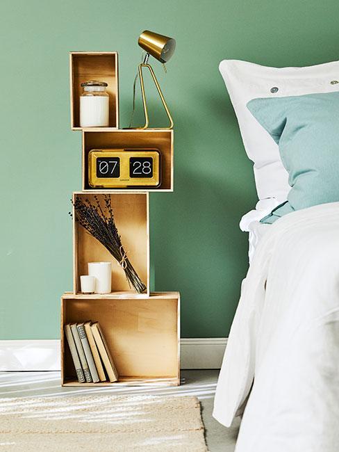 szafka nocna zrobiona ze skrzynek na tle zielonej ściany