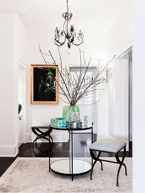 Przedpokój ze stolikiem pośrodku, obok dwa siedziska, wazon na stole