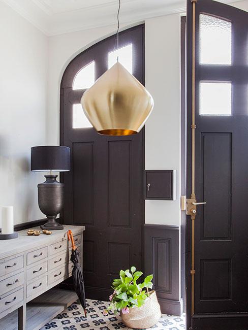 Elegancki przedpokój z czarnymi drzwiami, czarną lampą i jasną szafką