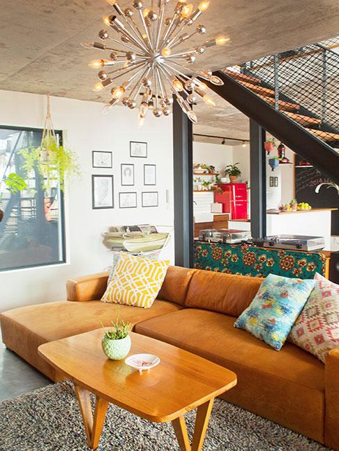 loft z brązową skórzaną sofą i okazałym żyrandolem