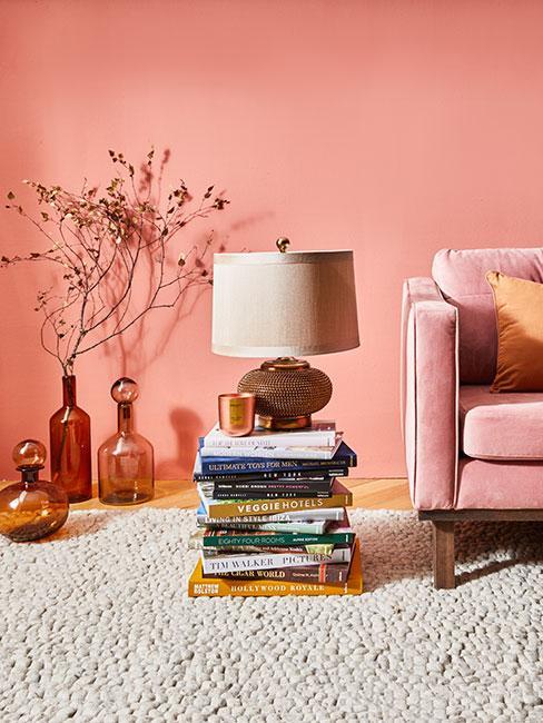 Kanapa, lampa i wazony z kwiatami, w tle łososiowa ściana