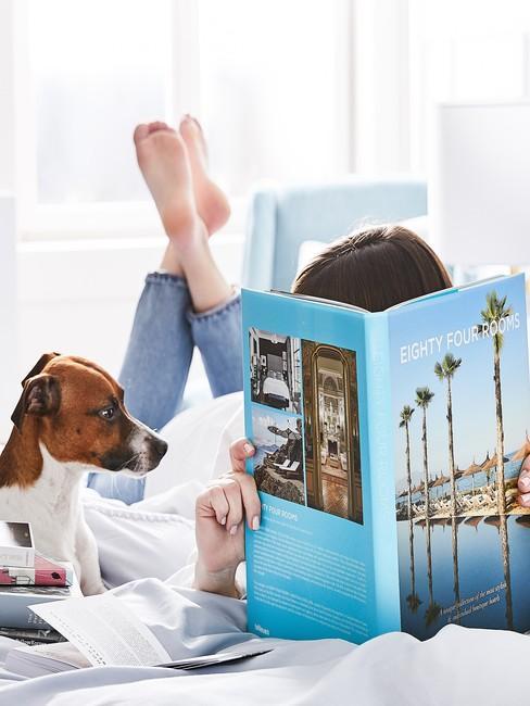 Kobieta czytająca książkę o podróżach, obok asystuje pies