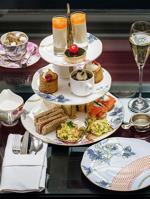 Angielski podwieczorek na etażerce z małymi kanapkami i deserami podany na pięknej porcelanie w kwiaty
