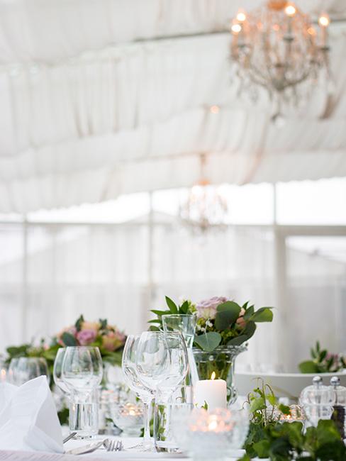 Stół udekorowany odświętnie kwiatami w namiocie weselnym