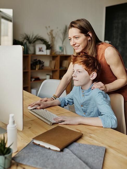 synek odrabiający lekcje przy komputerze z mamą