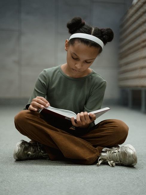 Dziewczynka siedząca na ziemi i czytająca najlepsze bajki