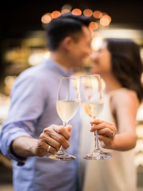 Uśmiechająca się para trzymająca kieliszki z szampanem - zaręczyny w restauracji