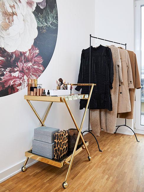 Otwarta szafa kapsułowa obok stołu pomocniczego z kosmetykami