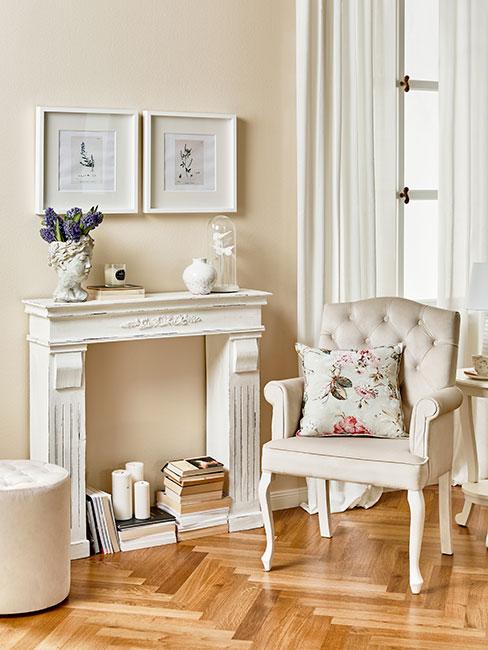 biała atrapa kominka obok pikowanego fotela w salonie w stylu prowansalskim