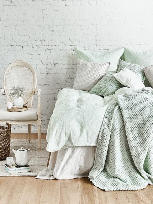 Sypialnia w odcieniach miętowej zieleni z ceglaną ścianą i bielony krzesłem w stylu shabby chic