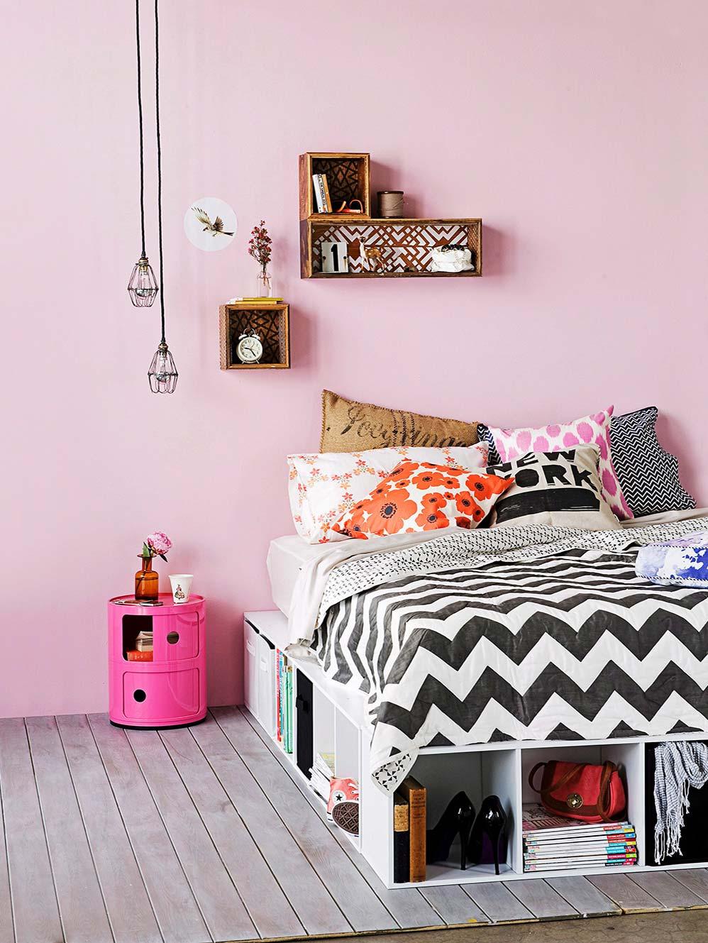 łóżko DIY z szuflad w sypialni z różową ścianą i półkami ze skrzynek na różowej ścianie
