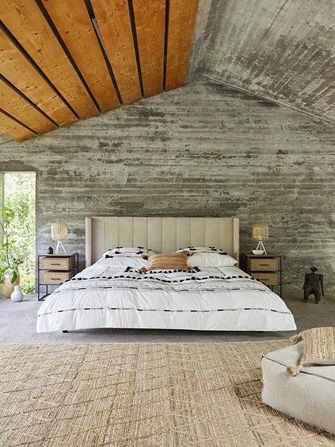 Duże łóżko w sypialni z szarego betonu w lofcie