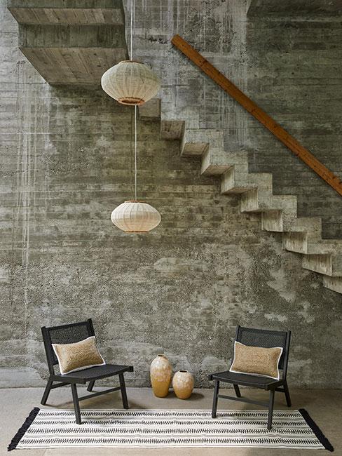 kącik kawowoy z dwoma czarnymi ażurowymi fotelami w lofcie z szarego betonu