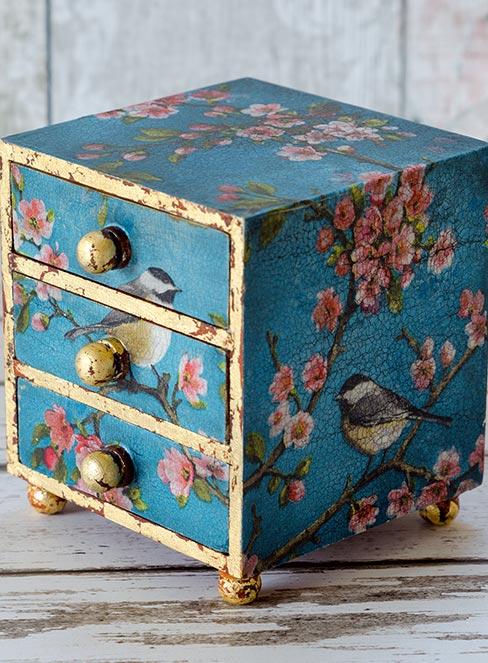 mała niebieska szkatułka z szufladami z kwiatami wiśni udekorowana techniką decoupage