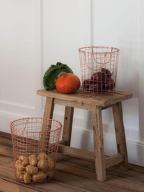 jesienne owoce i warzywa na drewnianym stołeczku, obok kosz z ziemniakami