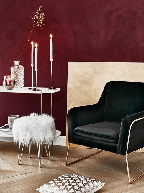 burgundowa ściana w salonie na tle czarnego fotela i pufa tapicerowanego białym futrem