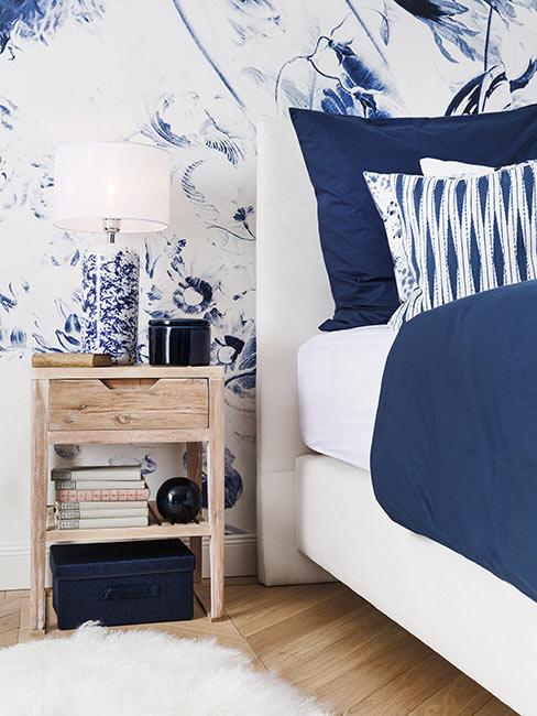 białe łóżko z granatowymi tekstyliami i ścianą w granatowe wzory