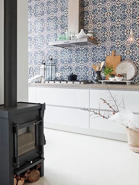 Jasne pomieszczenie z białą komodą różnymi dodatkami i ściana wyłożoną tapetą w granatowo-biały wzór