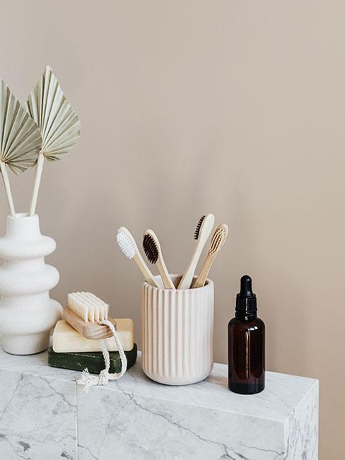 Dodatki łazienkowe na marmurowym blacie na tle ściany w kolorze nude