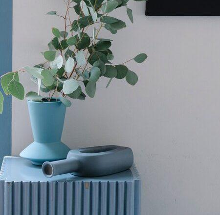 Dodatki w kolorze błękiku na błękitnej szafeczce na tle białej ściany