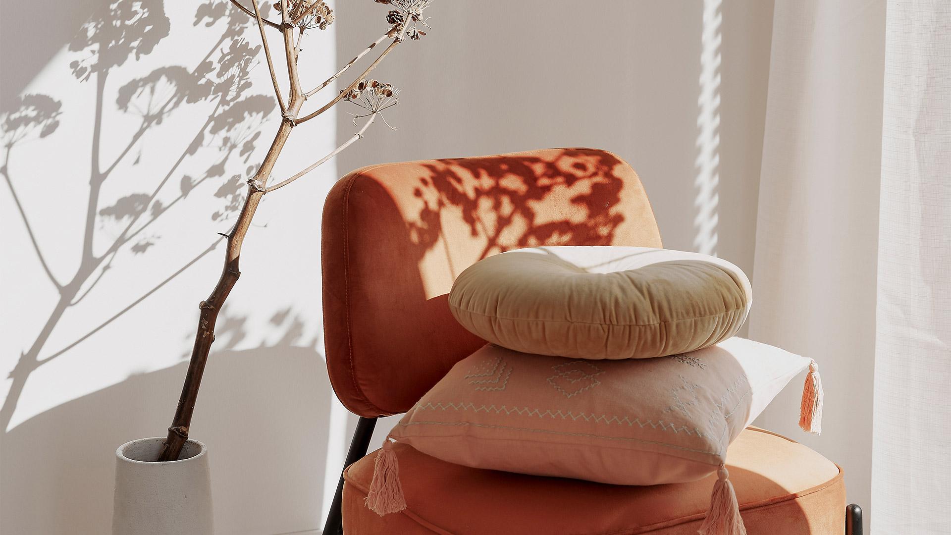 pomarańczowe krzesło z beżowymi poduszkami