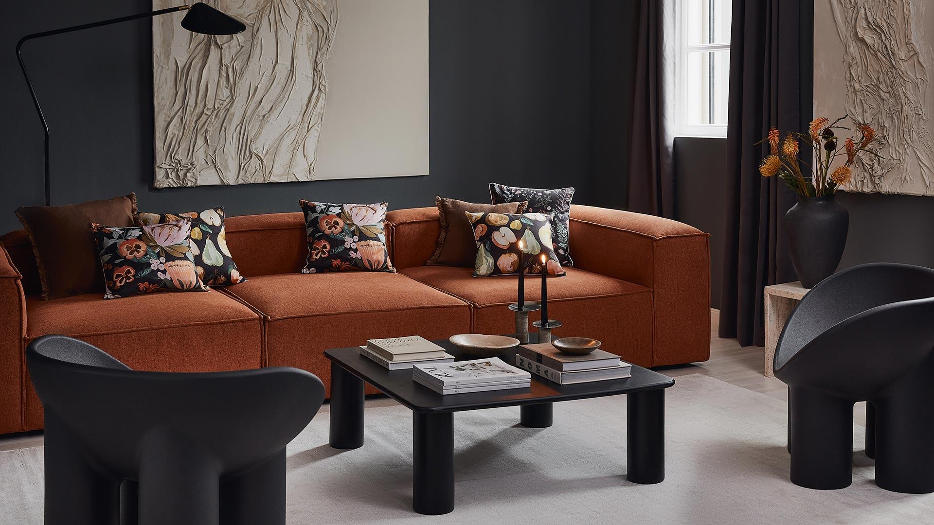 Tło na zoom ze zdjęciem salonu z pomarańczową sofą i kolorowymi poduszkami