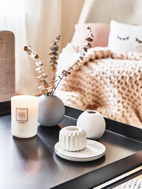 Dwa wazony, jeden biały, drugi beżowy ustawione na ciemnym stoliku z kamienia, obok białe ozdoby