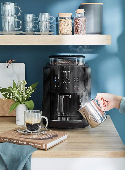 Nowoczesny czarny ekspres do kawy na tle niebieskiej ściany