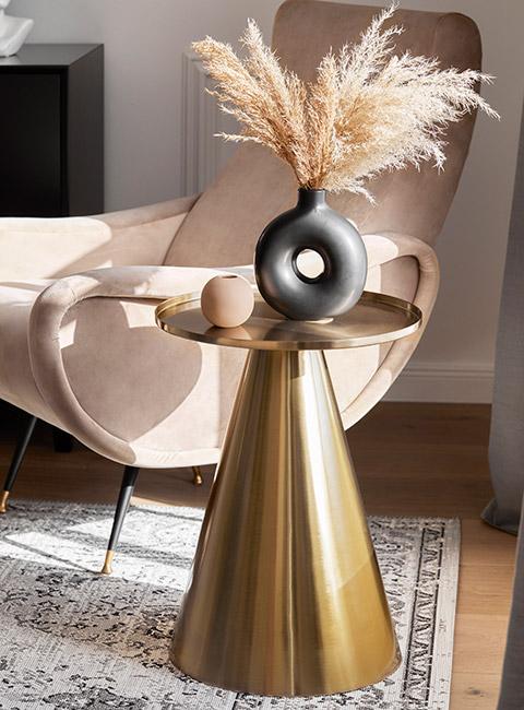 designerski złoty sto z trawą pampasową czarnym wazonem