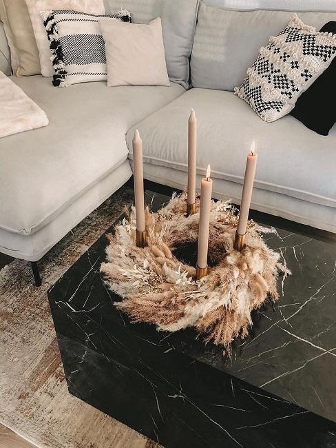 Stroik bożonarodzeniowy na stole z marmuru zrobiony z suszonych traw i świeczek
