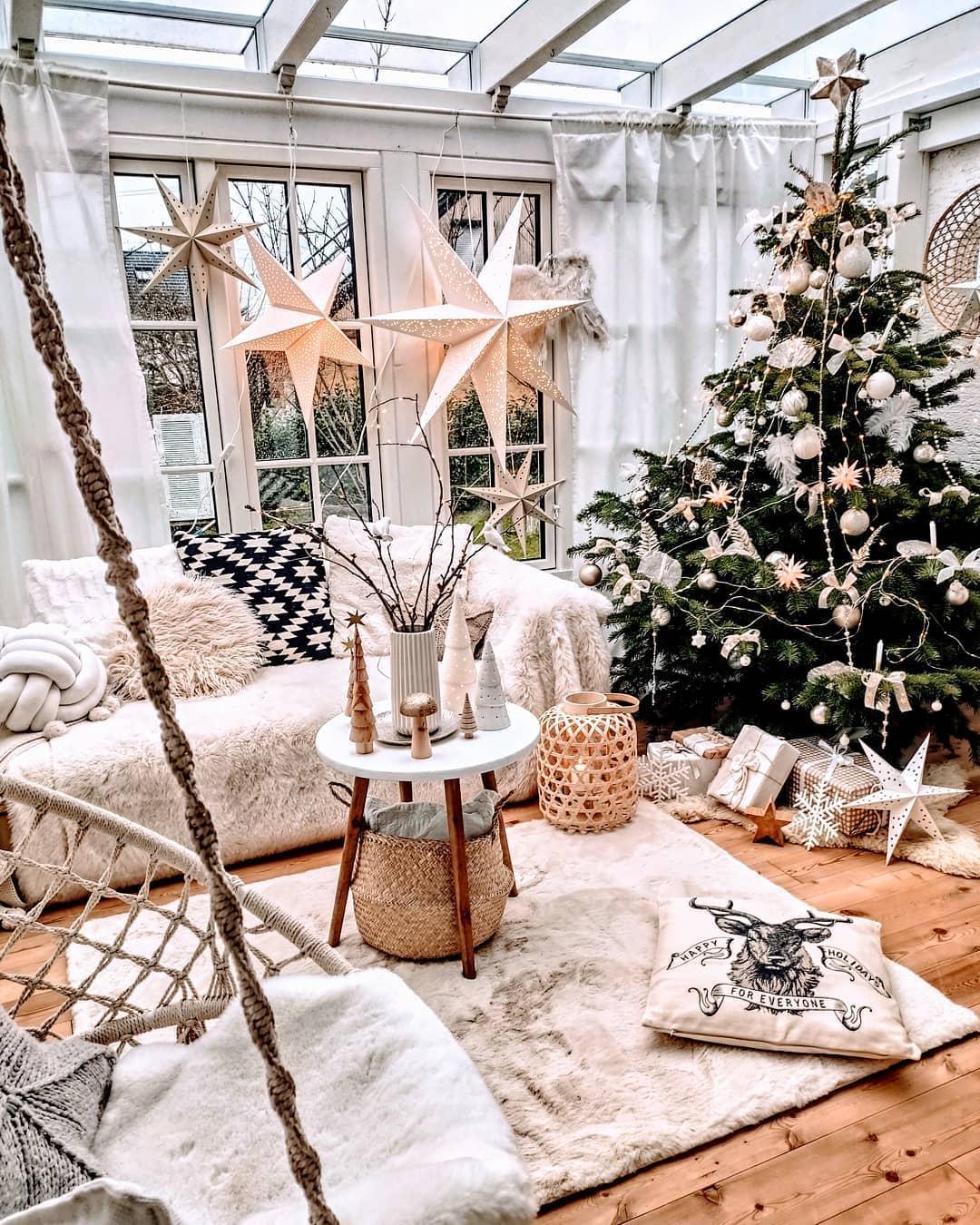 Zielona choinka z białymi dekoracjami w salonie boho