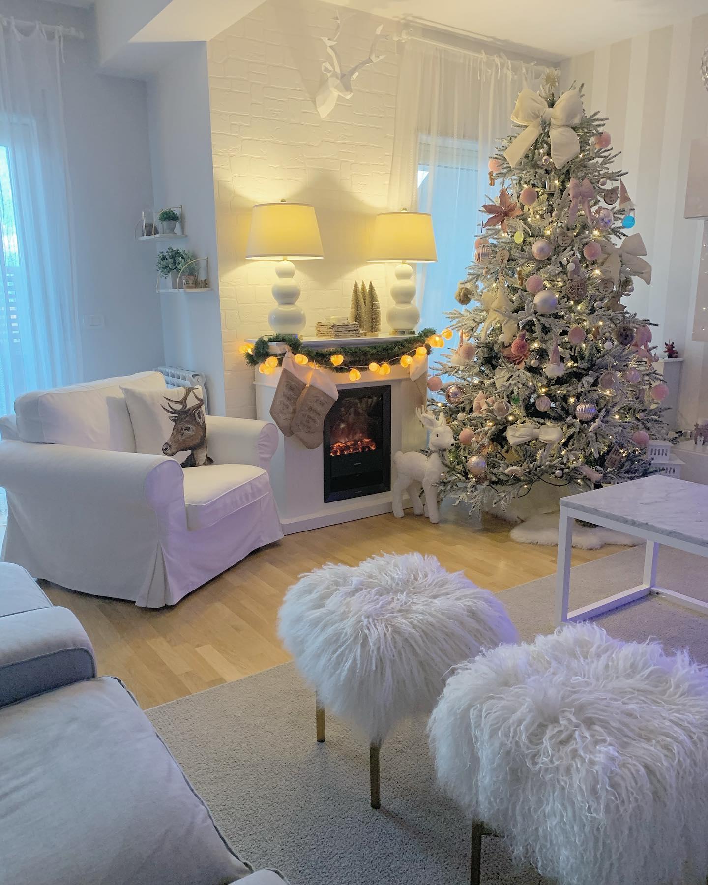Choinka z białymi i złotymi dekoracjami w małym salonie z kominkiem