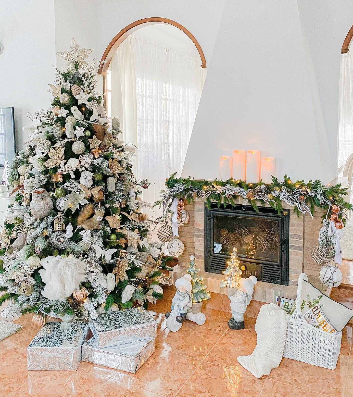 Choinka z białymi i złotymi dekoracjami w małym salonie z kominkiem