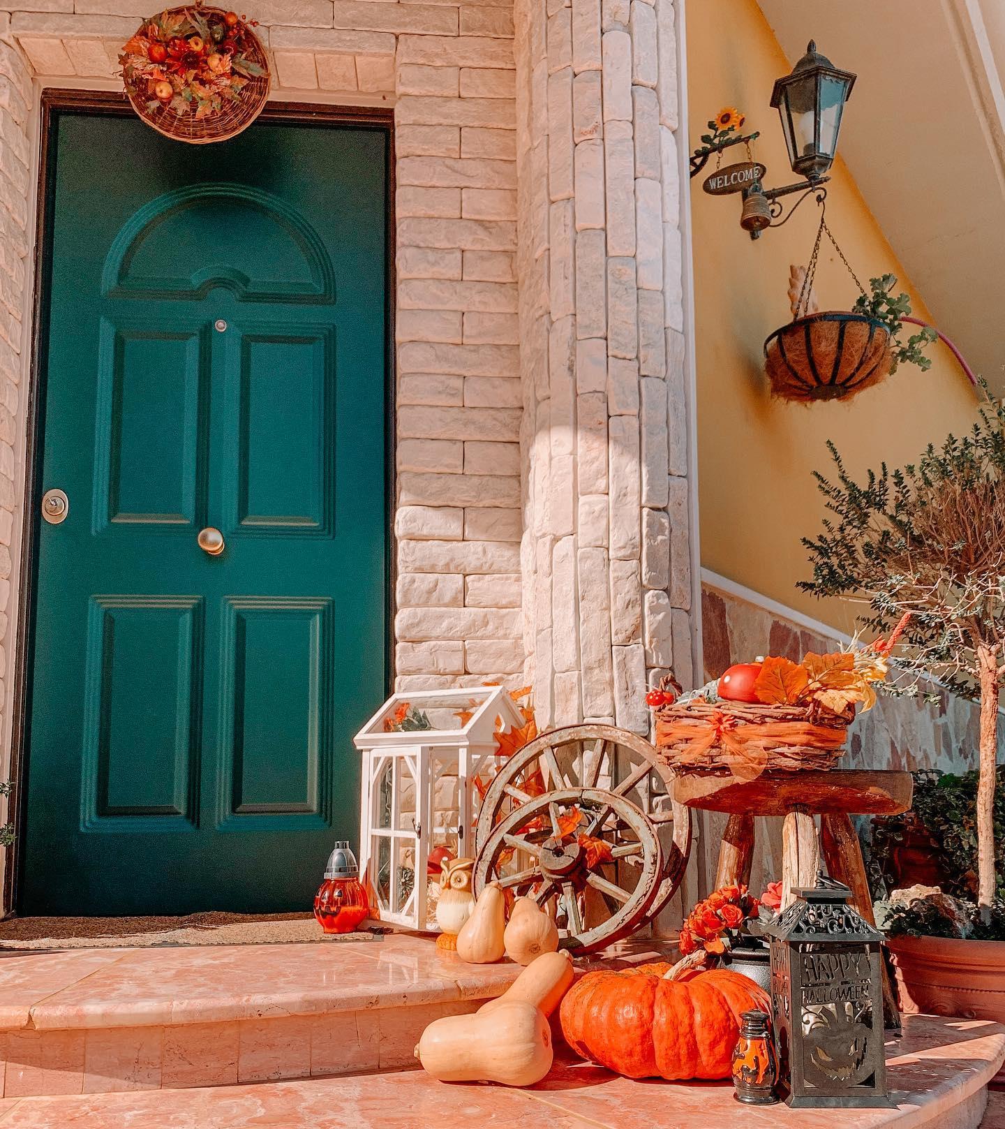 Jesienne dekoracje z dyni przed niebieskimi drzwiami wejściowymi