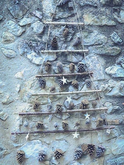 jak zrobić choinkę: choinka z patyków, sznurka i szyszek powieszona na ścianie