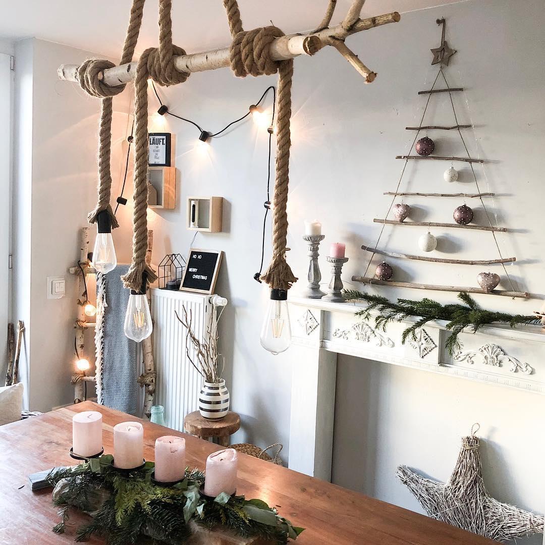 Jadalnia w stylu industrialnym z wiszącą lampą z żarówkami i choinką z patyków na ścianie