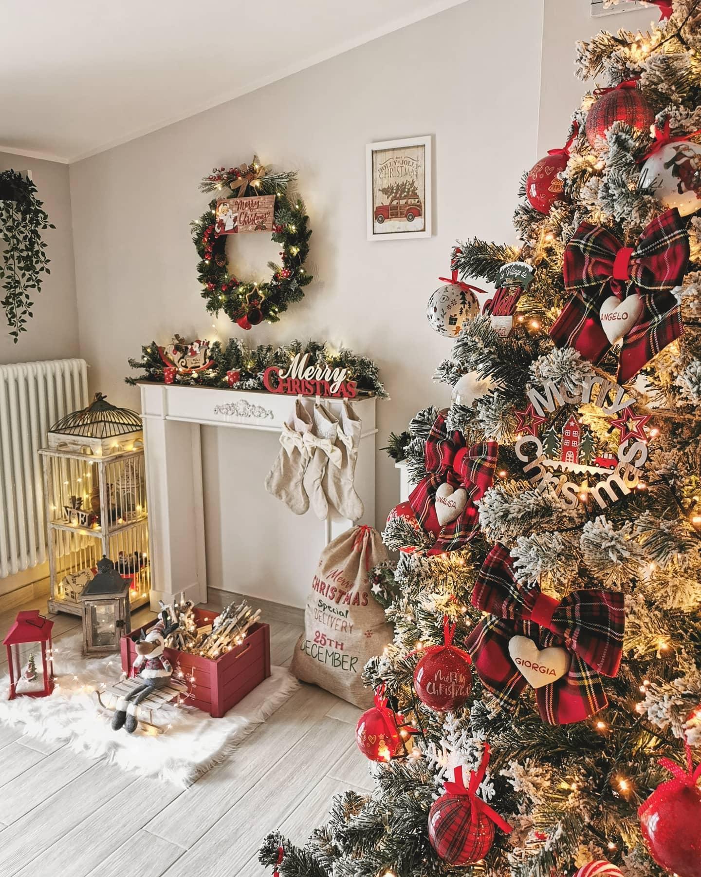 Choinka czerwono złota oprószona sztucznym śniegiem w jasnym rustykalnym salonie przy białym portalu kominkowym