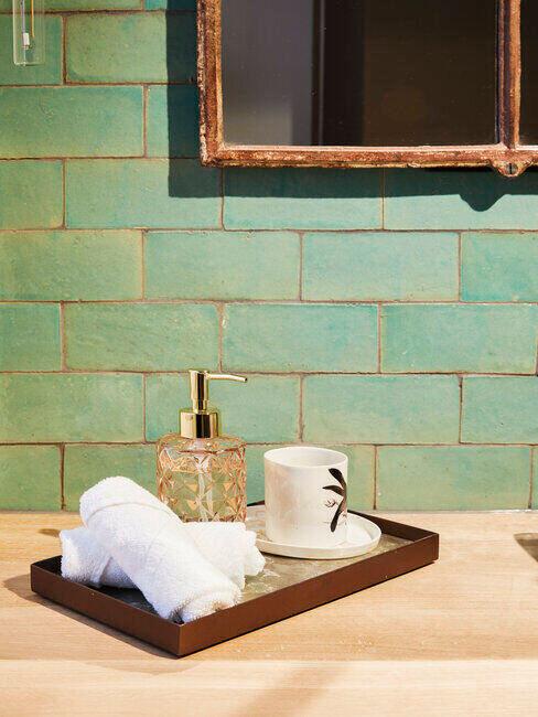 Zielona łazienka z drewniana tacką i innymi dodatkami