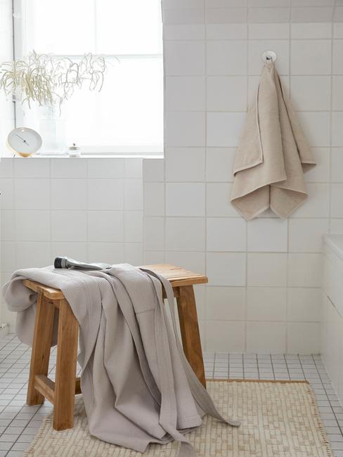 drewniany stołek z ręcznikiem w białej łazience
