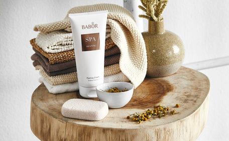 okrągły stołek w łazience na którym leżą ręczniki, mały wazon i kosmetyki