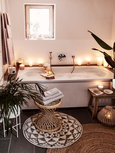 łazienka biała z drewnem: Zabudowana biała wanna w łazience, wokół świeczki i dodatki w stylu boho
