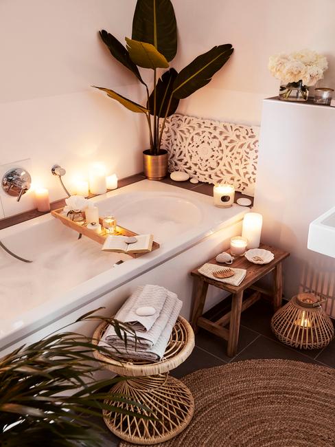 łazienka biała z drewnem: Zabudowana biała wanna w łazience, wokół świeczki i dodatki w stylu boho