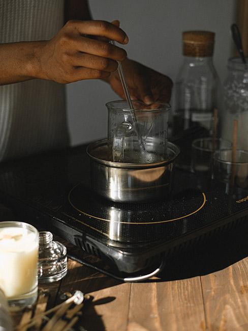 Osoba stojąca przy kuchence, topiąca wosk do wróżb