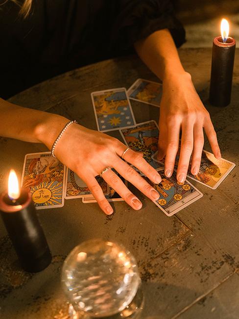 wróżby andrzejkowe: Dłonie położone na stole nad kartami tarot