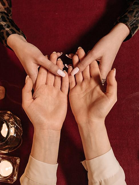 Dwie osoby trzymające się za ręce, jedna wróży drugiej z ręki