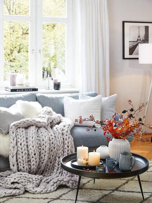 Ujęcie na stolik w salonie, obok kanapa z kocem